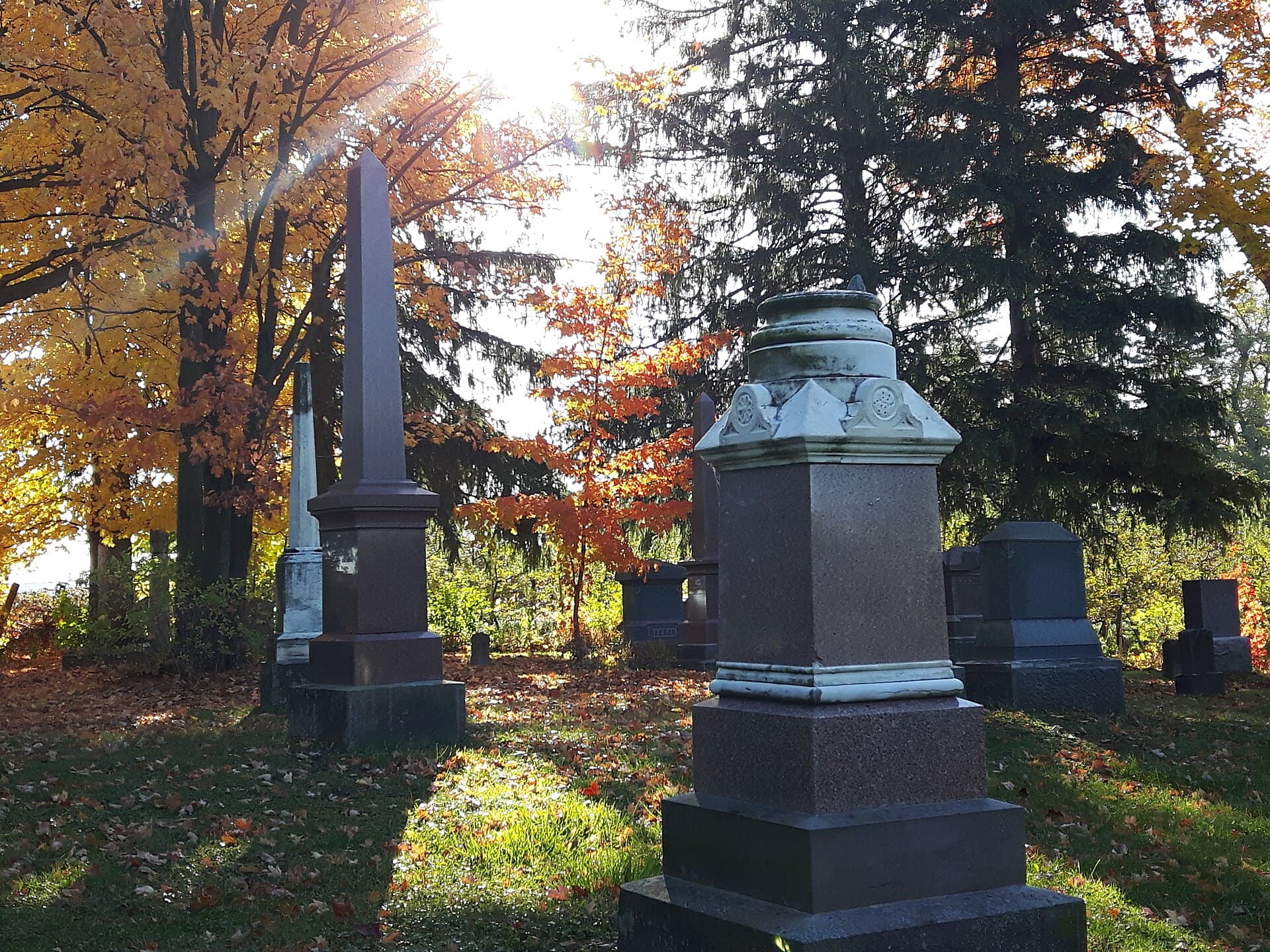Old monuments under autumn maples at the edge of a historic cemetery